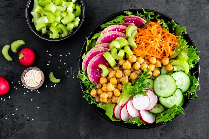 Salad Buddha bowl with fresh cucumber, celery, watermelon radish, raw carrot, lettuce, radish and chickpea for lunch. Healthy vegetarian food. Vegan vegetable dish. Top view. Salad Buddha bowl with fresh cucumber, celery, watermelon radish, raw carrot, lettuce, radish and chickpea for lunch. Healthy vegetarian food. Vegan vegetable dish. Top view